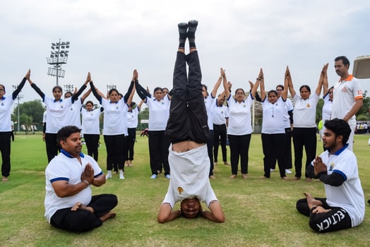 New Delhi, India, June 21, 2023 - Group Yoga exercise session for people at Yamuna Sports Complex in Delhi on International Yoga Day, Big group of adults attending yoga class in cricket stadium photo