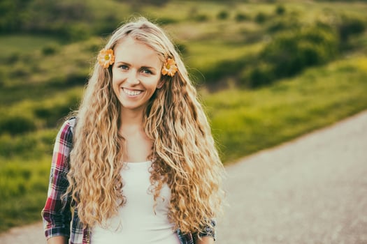 Portrait of beautiful blonde woman with flowers in her hair at the country road.Toned image. photo