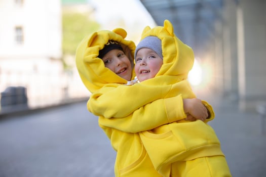 Little brother and sister. Funny children boy and girl in yellow suits hug each other. photo