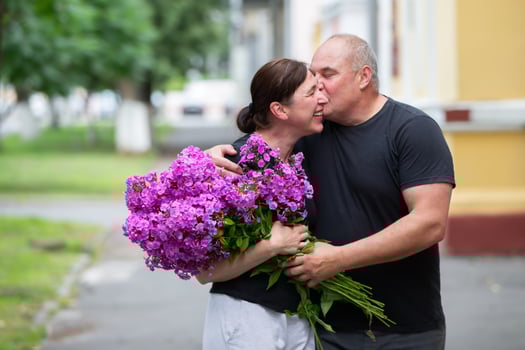 A happy elderly couple with a bouquet of flowers walks around the summer city. photo
