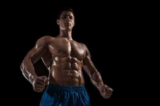 Muscular and fit young bodybuilder fitness male model posing over black background. photo