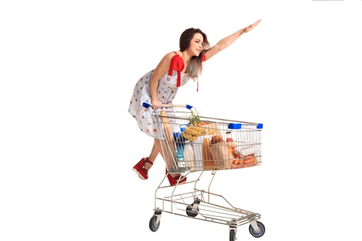 Woman with shopping cart full with products isolated over white background photo
