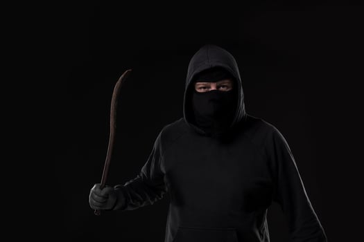 Male offender masked with a scrap. On black background at the studio photo