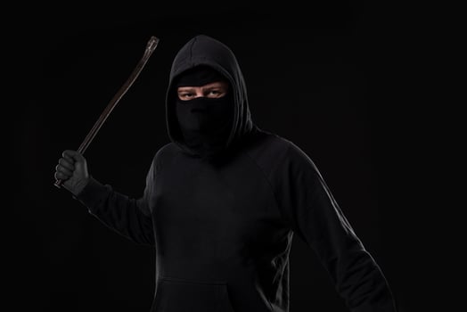 Male offender masked with a scrap. On black background at the studio photo