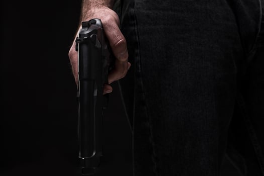 Killer with gun on black background at the studio photo