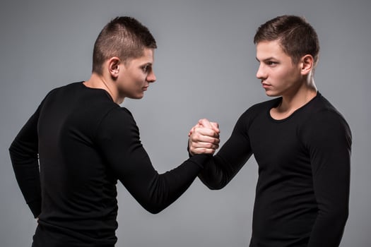 Portrait of young twin brothers standing face to face on gray ba photo