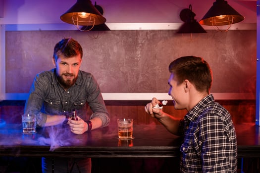 Vaping man holding a mod. A cloud of vapor at the vapebar. photo