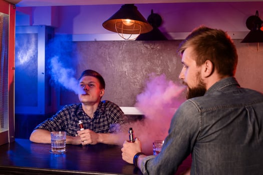 Two young men smoke electronic cigarettes in a vapebar photo