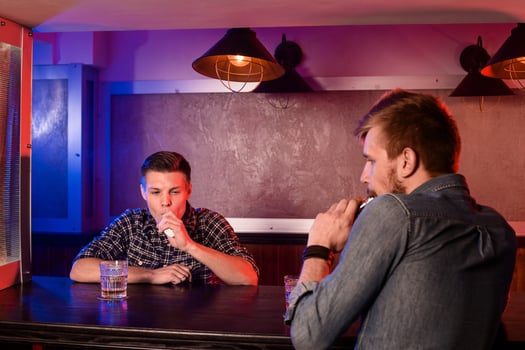Two young men smoke electronic cigarettes in a vapebar photo
