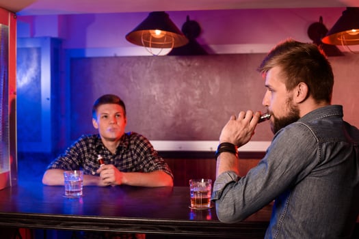 Two young men smoke electronic cigarettes in a vapebar photo
