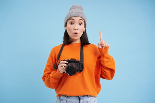 Passionate asian girl photographer, taking pictures on her digital camera, capturing moments outdoors, shooting photos, blue background photo