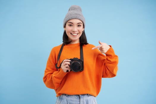 Passionate asian girl photographer, taking pictures on her digital camera, capturing moments outdoors, shooting photos, blue background photo