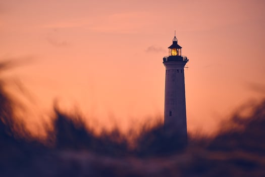 Lighthouse in warm morning glow above the dunes photo