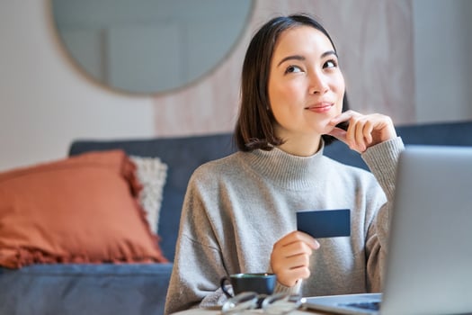 Happy smiling girl with credit card, paying her bills online on computer, doing shopping on her laptop, sitting at home photo