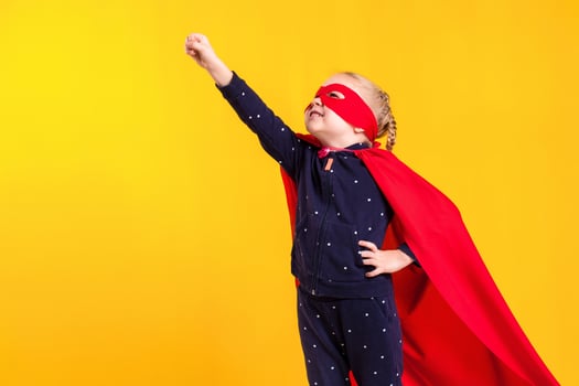 Funny little power superhero child girl in a red raincoat and a mask. Superhero concept. photo