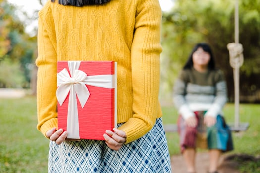 Girl holding a red gift box standing in the garden photo