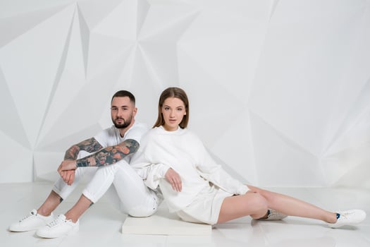 Casual couple near a white wall, man and woman in white clothing. photo