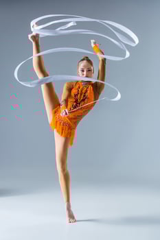 teenager doing gymnastics dance with white ribbon on a blue back photo
