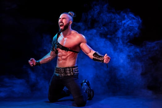 Handsome young sexy man with beautiful muscular chest in interesting costume on the scene photo