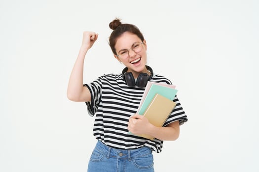 Enthusiastic young woman in glasses, teacher celebrating, raising hand up and cheering, tirumphing with joyful smile, white background photo