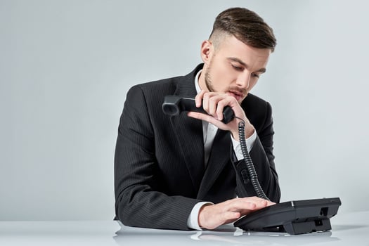 young man dials the phone number while sitting in the office photo