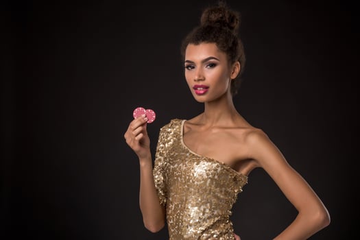 Woman winning - Young woman in a classy gold dress holding two red chips, a poker of aces card combination. photo