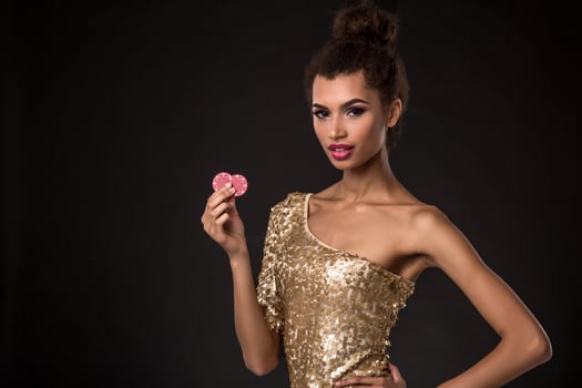 Woman winning - Young woman in a classy gold dress holding two red chips, a poker of aces card combination. photo
