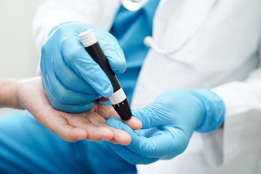 Asian doctor using lancet pen on senior patient finger for check sample blood sugar level to treatment diabetes. photo