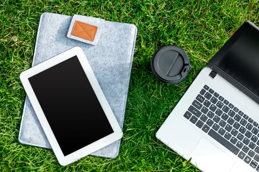 Laptop computer on green grass with coffee cup and tablet in outdoor park photo