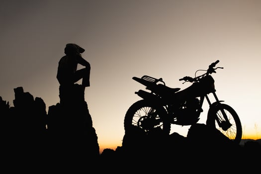 Man with motocross bike against beautiful lights, silhouette of a man with motocross motorcycle On top of rock high mountain at beautiful sunset, enduro motorcycle travel concept. photo