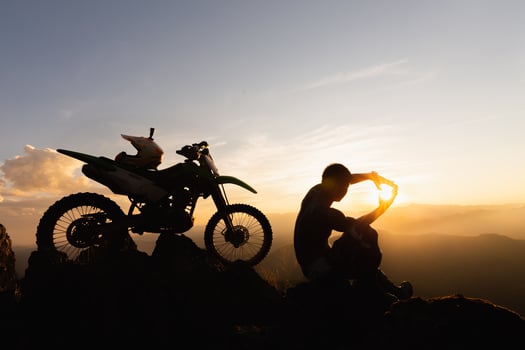 Man with motocross bike against beautiful lights, silhouette of a man with motocross motorcycle On top of rock high mountain at beautiful sunset, enduro motorcycle travel concept. photo