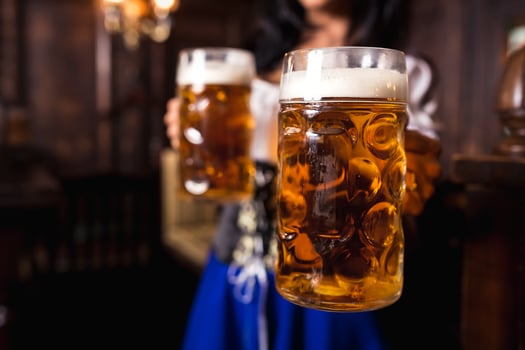 Young sexy Oktoberfest waitress, wearing a traditional Bavarian dress, serving big beer mugs at bar. photo