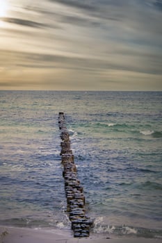 Groynes jut out into the Baltic Sea. Sunset on the horizon. Wooden logs protecting photo