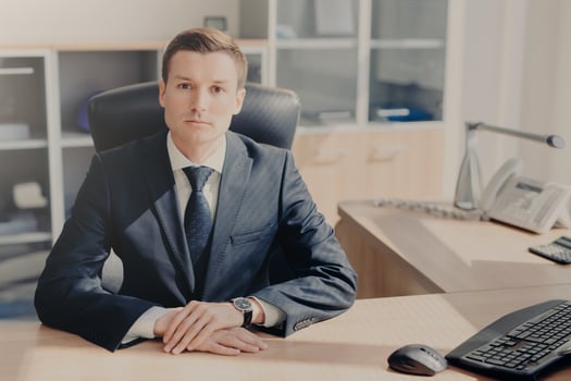 Serious businessman seated at a desk in a well-lit office, poised and ready for work photo