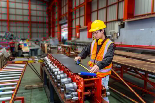 Asian industrial worker is checking the setup value of metal sheet roll forming machine inside roof factory for safety industry construction photo