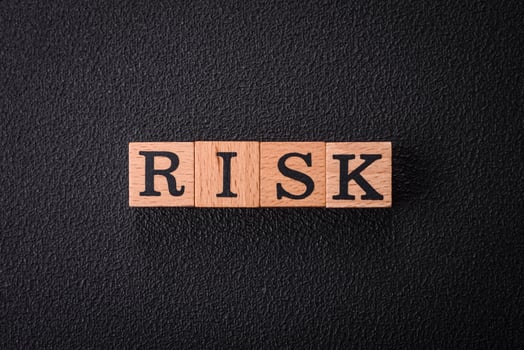 The inscription risk with wooden cubes on a dark concrete background photo