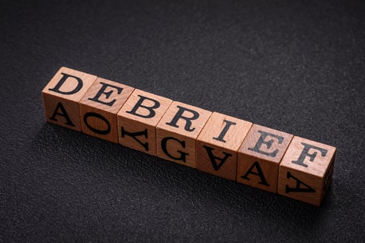 The inscription debrief in wooden cubes on a dark concrete background photo