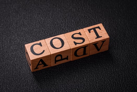 The inscription cost in wooden cubes on a dark concrete background photo