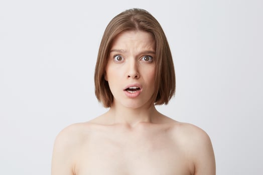 Cropped shot of amazed embarresed young woman with dark hair and healthy skin feels confused and surprised isolated over white background Standing half naked after shower photo