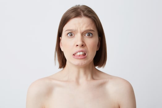 Horizontal shot of sad worried young woman with perfect skin after applying mask or cream after shower feels stressed and have problems isolated over white backgound photo