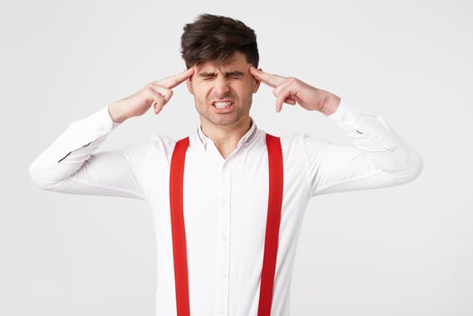Portrait of young man isolated on white background, suffering from severe headache, pressing fingers to temples, closing eyes photo
