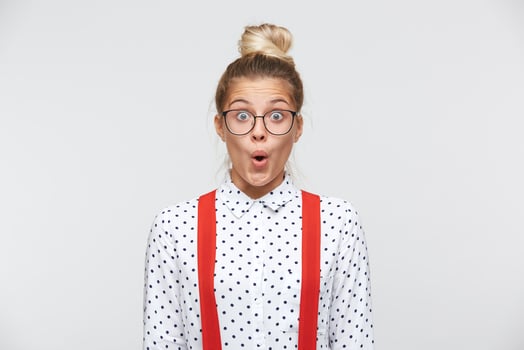 Surprised facial expression. Have look at that amazing thing Portrait of shocked female lowered jaw from surprise, feels stupefied, being impressed by something. In a white shirt, red suspenders photo