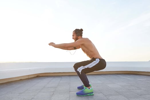 Portrait of young bearded man with fit athletic body doing stretching exercises, listening music on headphones, has muscular body shape. photo