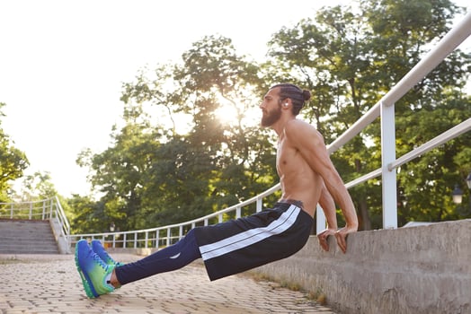 Young sporty bearded man doing warm-up before jogging, leads healthy active lifestyle, looks away. Fitness male model. photo
