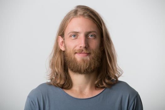 Portrait of smiling handsome bearded young man with blonde long hair wears gray t shirt feels happy and confident isolated over white background photo