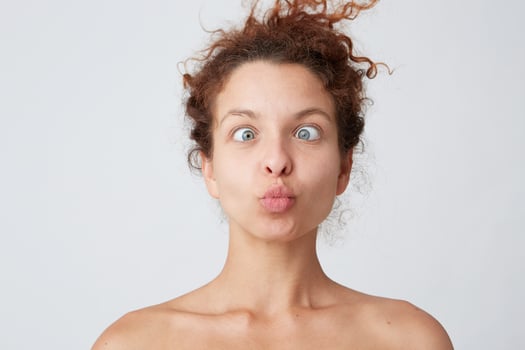 Horizontal shot of amazing crazy young woman with curly hair and perfect skin making funny face and joking isolated over white background Joyful girl having fun after taking shower photo