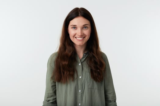 Cheerful young beautiful long haired brunette female showing her white perfect teeth while smiling happily, dressed in casual clothes while posing over white background photo