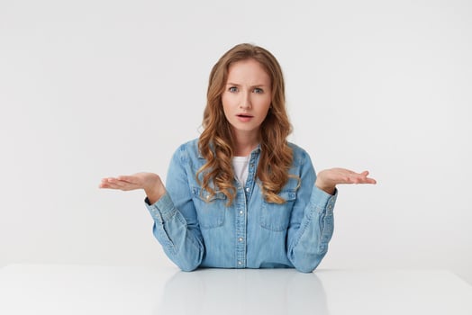 Confused young woman with long blond wavy hair, throwing up his arms in bewilderment, looks skeptically displeased indignantly with incomprehension, over white background. photo