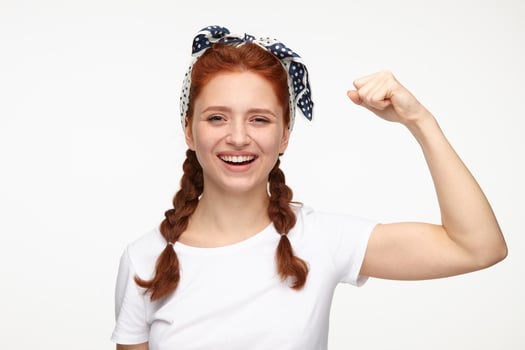 portrait of young ginger female standing over white studio background smiles and shows her muscles photo