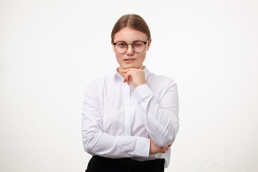 Thoughtful young white-headed woman with natural makeup touching her chin with raised hand while looking pensively at camera and biting underlip, isolated over white background photo